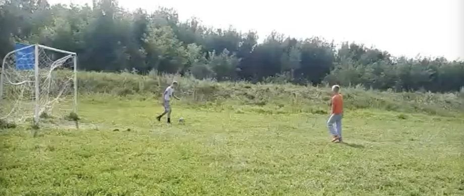 Глеб Пополитов играет в футбол на деревенском поле