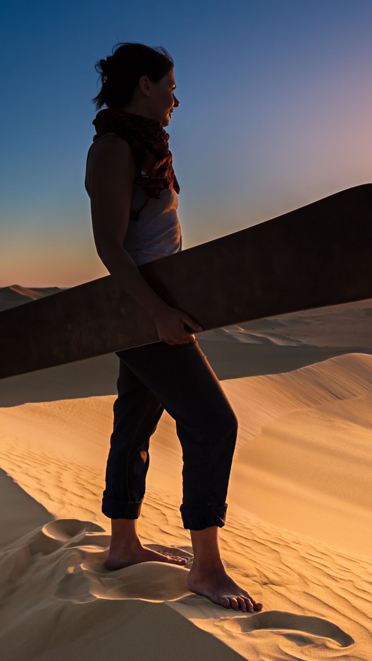 Девушка гоняет на доске по песчаным дюнам 