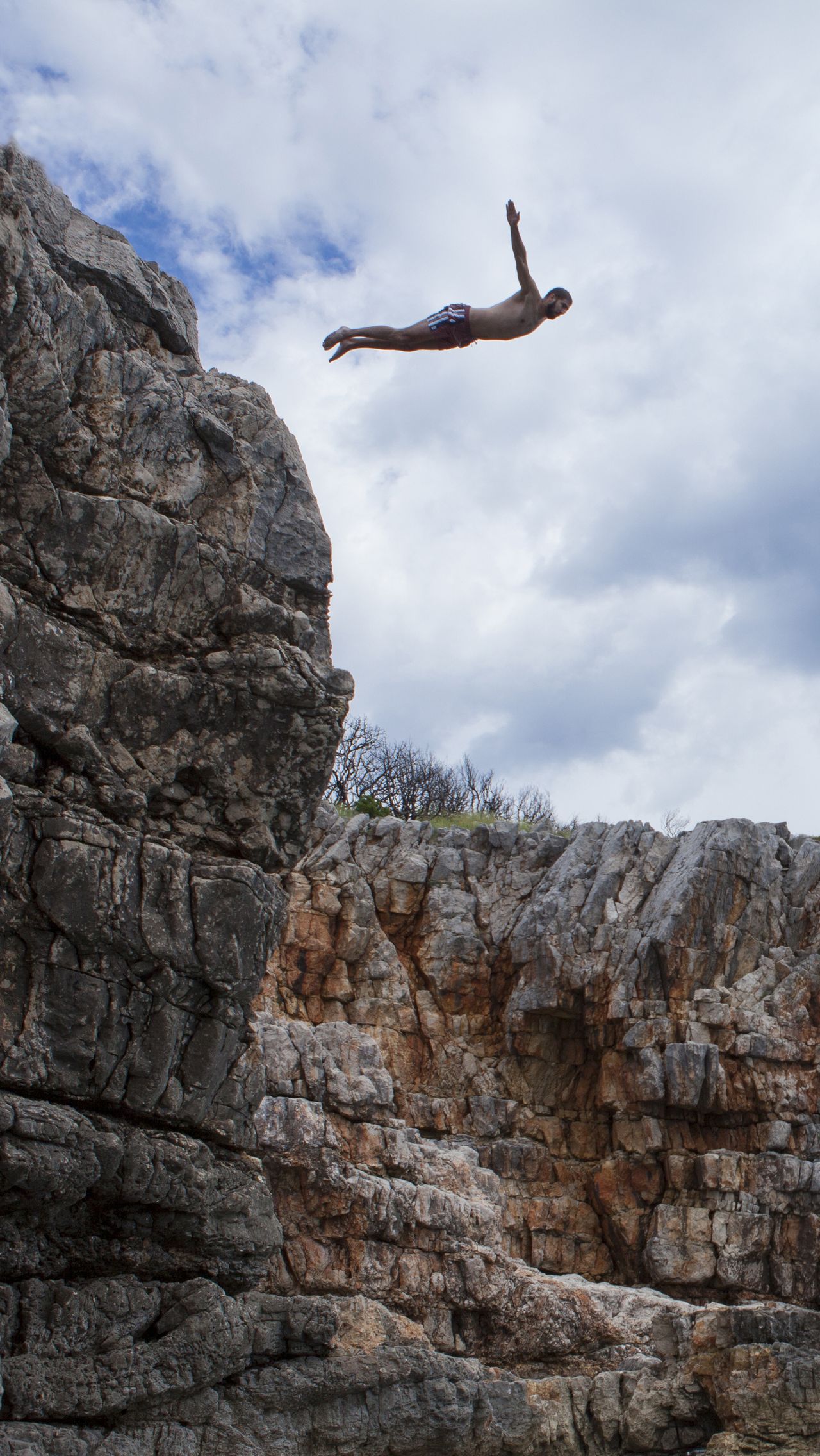 Экстремальный прыжок со скалы с селфи-палкой в одной руке и верёвкой — в другой