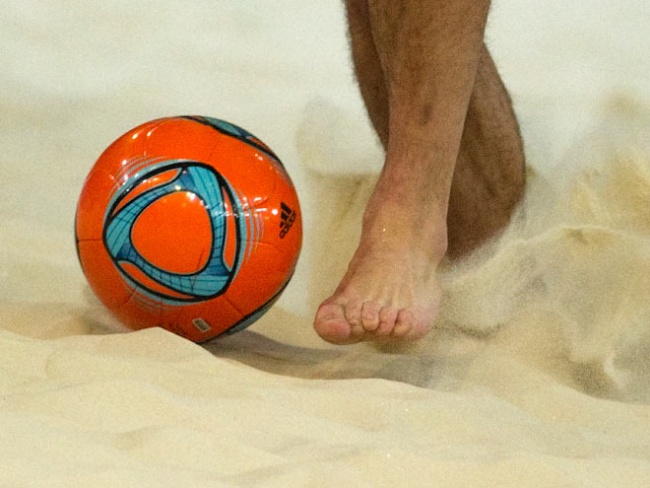 Нога, мяч и песок